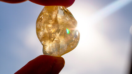 A citrine stone held towards the sun in close-up