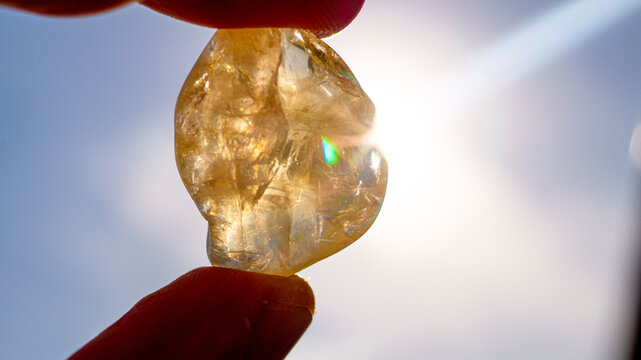 A citrine stone held towards the sun in close-up