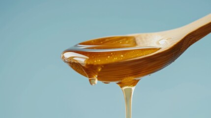 Honey dripping off wooden spoon. - obrazy, fototapety, plakaty