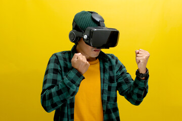 Asian man wearing a VR headset enthusiastically plays a fighting game in virtual reality. Isolated on a yellow background.