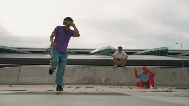 Group of asian break dancer perform street dance with multicultural friend support and moving hip hop music. Attractive handsome hipster practice b boy dance at street. Outdoor sport 2024. Sprightly.
