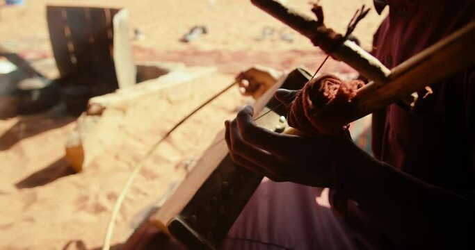Authentic Arab Bedouin plays Music on Rebab String Instrument in Wadi Rum Desert in Jordan, Middle East. Local Traditional Culture and Hospitality. 4K closeup handheld shot