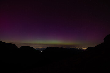 Aurora borealis. Northern lights in winter mountains. Sky with polar lights and stars. Stars reflection in lake water and the northern lights.