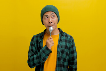 Portrait of an Asian man contemplates menu recipes for his meal preparations, gazing at an empty space designated for notes, captured against a yellow background