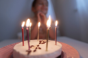 Happy child looks at a cake with candles. girl makes wishes, dreams or prays. celebrates birthday.