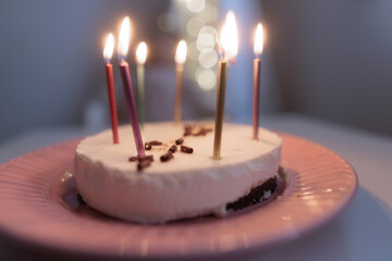 Happy child looks at a cake with candles. girl makes wishes, dreams or prays. celebrates birthday.