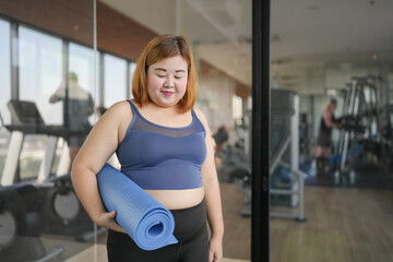 Obraz premium Obese asian woman diet holding yoga mat for training yoga&nbsp;exercising&nbsp;fitness workout and health concept. training working out at gym