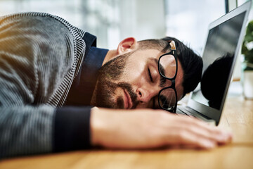 Businessman, sleeping and tired with laptop in office for burnout, exhausted or overworked by...