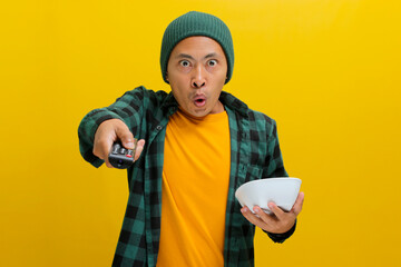 Startled young Asian man, adorned in a beanie hat and casual shirt, wearing a shocked expression,...