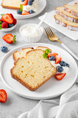 Delicious vanilla pound cake served with fresh berries and whipped cream on a gray concrete background. Selective focus, copy space.