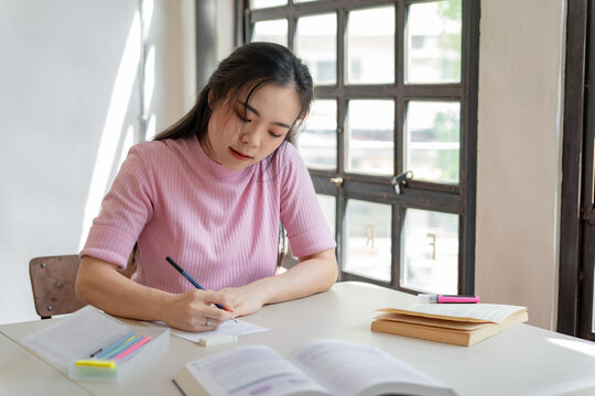 Asian girl student doing exam hand holding pencil writing answer in university classroom education high school or university student taking notes while preparing for exam - Powered by Adobe
