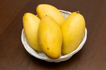 Delicious ripe juicy mangos on wooden table, top view
