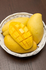 Mango. Close up of fresh ripe mango fruit with leaves over dark wooden table background with green...