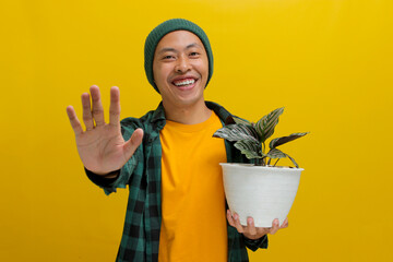 Asian man holds up a healthy Pin-stripe Calathea (Calathea ornata) houseplant in a white pot and...