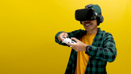 Young Asian man wearing a VR headset enjoys playing a video game in virtual reality, holding a...