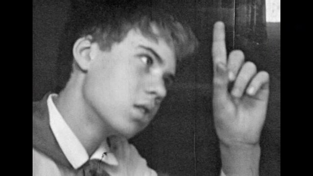 Doubt teen boy shrugging shoulders, portrait, archive film. Confused unsure pioneer. Puzzled young man at Soviet home. Look guilty, make excuses. Vintage black white film. Family archive. Retro 1980s
