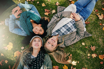 Top view, teen girls on grass for lying, relaxing and bonding together in park with happiness. Nature, lawn and friends on summer holiday for chilling, hanging out and laugh outdoors with smile