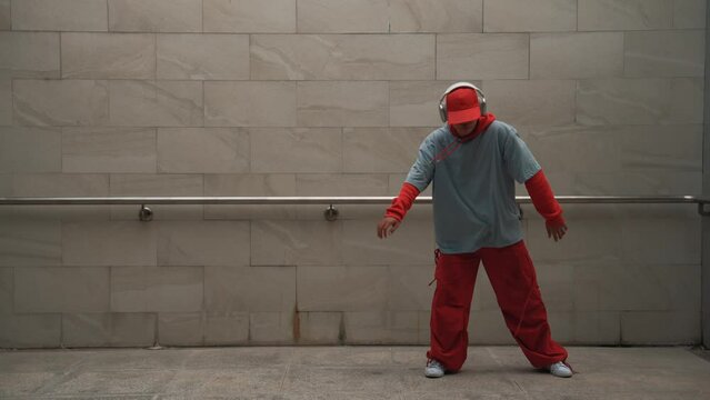 Handsome choreographer practice street dance in gray background. Young attractive b boy dancer perform while wearing stylish cloth. Feeling of lively step. Copy space. Outdoor sport 2024. Sprightly.