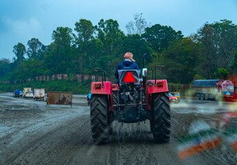Fototapeta premium Tractor Back View in a muddy road under construction shot by Sony ALPHA ILCE-6400 under overcast conditions