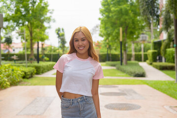 Portrait of beautiful Asian girl with blonde hair smiling outdoors