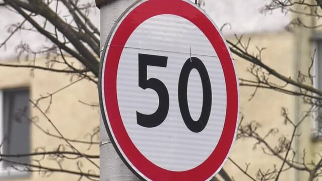 Round speed limit road sign on the road. 50 km per hour. Circle road sign with number 50, installed beside a road in rural. Speed limit for 50 km. Warning to slow driving on street. 
