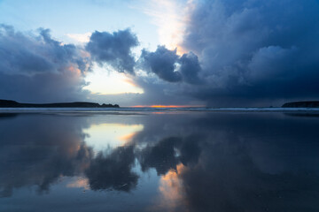 Les nuages menaçants reflètent leurs teintes sur le sable mouillé d'une plage de la presqu'île...