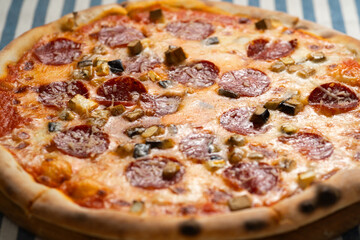 Italian pizza with smoked pepperoni sausage, parmesan cheese and wild mushrooms in a pizzeria on...