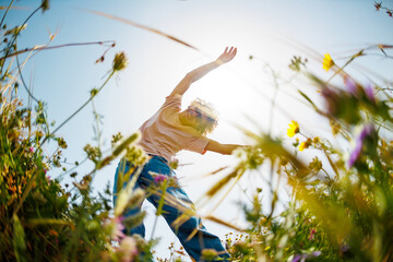 Summer mood. a young and cheerful guy posing against a background of blue sky and flowers. A handsome man dances among flowers. the guy is dancing.
