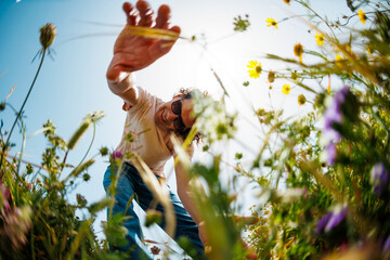 Summer mood. a guy touches flowers while walking through a meadow. a man collects flowers in a...