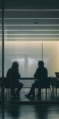 Two men are sitting in chairs in a room with glass windows.