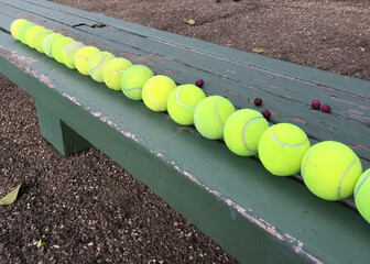 Row of used tennis balls on a bench