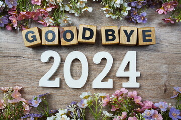 Goodbye 2024 years number with flowers frame top view on wooden background