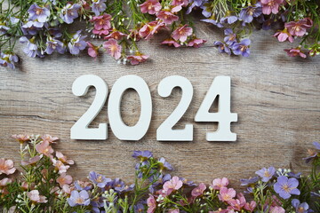 2024 years number with flowers frame top view on wooden background. Hello, Welcome and Goodbye new year concept