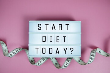 Start diet today? letterboard text on LED Lightbox and Measuring tape on pink background,...