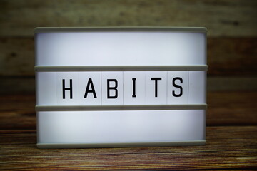 HABITS letterboard text on LED Lightbox on wooden background, business concept background