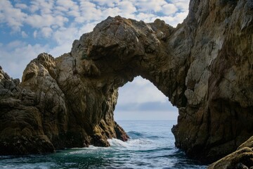 Breathtaking coastal rock arch with sunlight filtered through the clouds