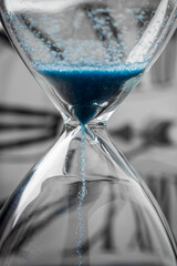 Blue sand hourglass on analog clock background
