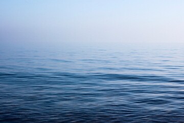 Calm blue sea water surface. Foggy horizon