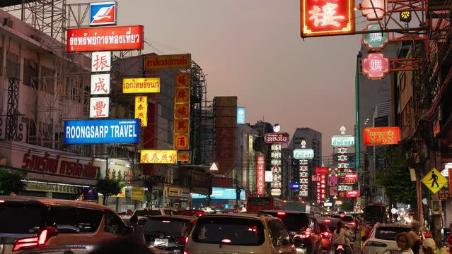 Bustling street scene at dusk in Bangkok's Chinatown with illuminated signs and heavy traffic. Bangkok Thailand. 5.01.2024