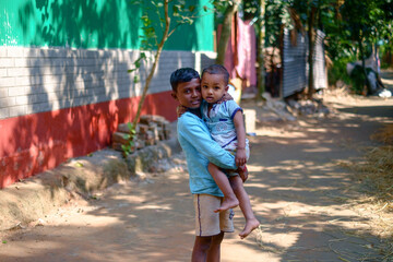 Portrait of south asian rural brothers , Young boy embracing  younger brother 