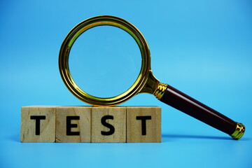 Test with wooden blocks alphabet letters and Magnifying glass on blue background