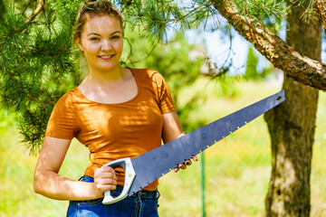 Female cuts branches of tree, using saw
