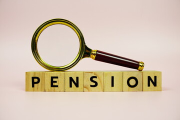Pension with wooden blocks alphabet letters and Magnifying glass on pink background