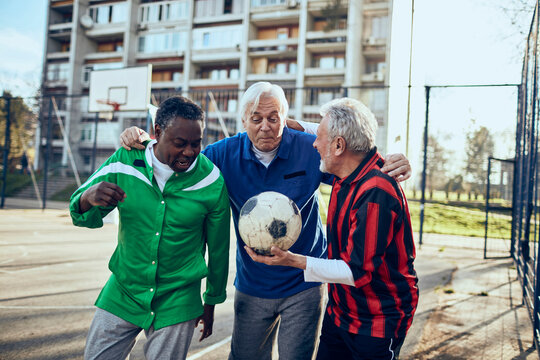 Senior friends discussing soccer tactics at a community sports field