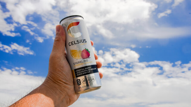 NORWALK, CT, USA- MAY 10, 2024: Man is holding can with energy drink with blue sky with clouds behind
