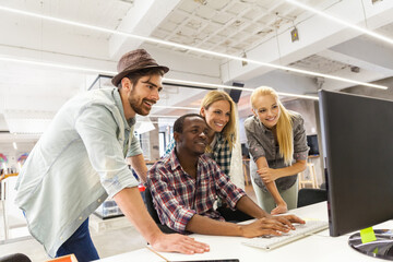 Diverse group of coworkers collaborating on a project using a computer in a modern office