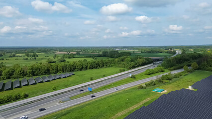 Drone view of a highway in Germany with a lot of traffic and many green fields around it.