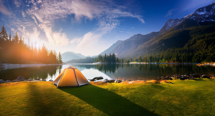 A tranquil morning at a mountain lake campsite. A tent sits near the calm waters, surrounded by lush greenery and towering peaks under the golden sunrise. Generative Ai. - Powered by Adobe