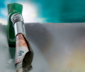 A gas pump with a dollar bill on top of it. The image is meant to be a commentary on the cost of...
