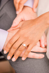 An interracial couple hold hands, her hand is on top of his